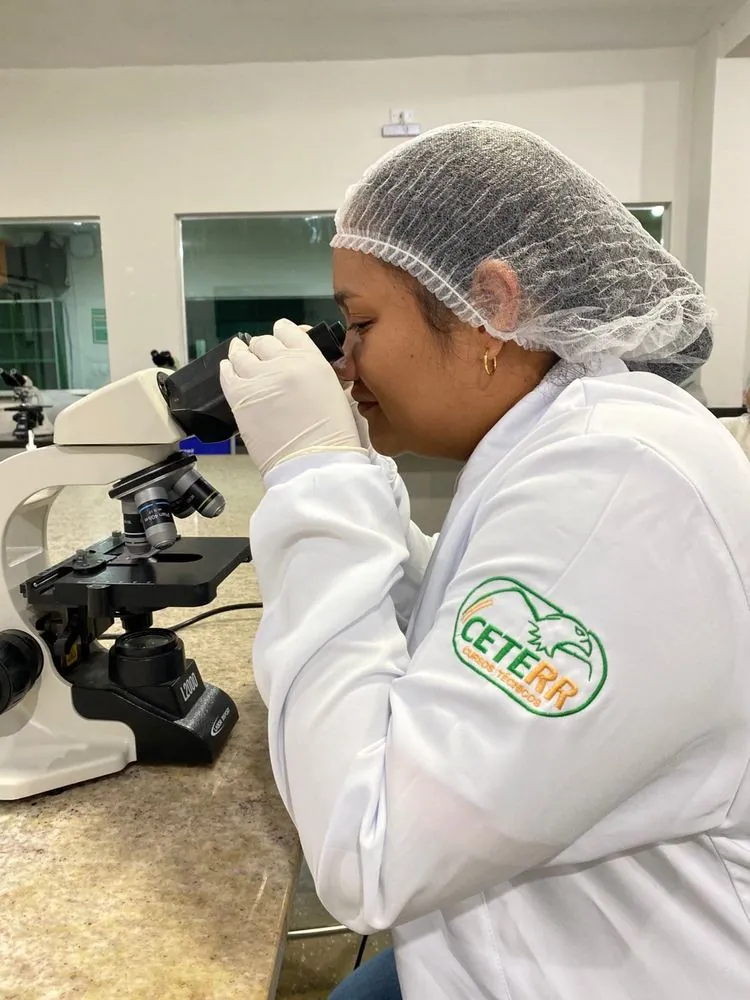 Aluna de Análises Clínicas usando microscópio